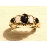 A 9ct gold sapphire & opal ring, the graduated claw set oval stones on a hallmarked gold band.