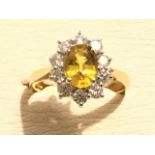 An 18ct gold sapphire & diamond cluster ring, the oval claw set yellow sapphire weighing two carats,