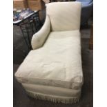 A contemporary chaise with shaped padded back and arm above a long loose cushion and sprung