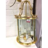 A brass hall lantern, with bevelled glass panels in circular enclosure around four candlelights,