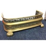 A small nineteenth century brass fender, with moulded curb on fluted bun feet beneath two pierced