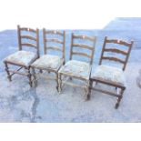 A set of four oak ladderback dining chairs with tapestry upholstered drop-in seats, raised on bobbin