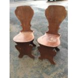 A pair of eighteenth century style mahogany hall chairs, with spade shaped backs above rounded seats