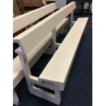 A painted pew with angled plank seat on square columns, the backrest with shelf behind for hymbooks.