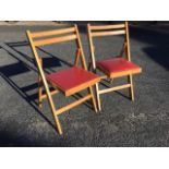 A pair of folding beech chairs with red vinyl upholstered seats. (2)