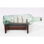 Early 20th century ship in a bottle with three masts and flying British flag on stand, 27.