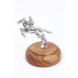 A vintage Desmo chrome plated car mascot in the form of a jumping horse and jockey, on wooden base,