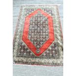 Good Persian silk rug, brick-red ground centred by elongated foliate medallion,