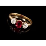 Ruby and diamond three stone ring with an oval mixed cut ruby flanked by two old cut diamonds,