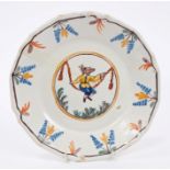 18th century French faience plate painted with a man on a swing within floral borders,
