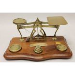 Early 20th century brass framed letter scales with table of letter rates and a set of five brass