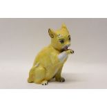 Mosanic pottery ornament of a yellow glazed cat licking its paw