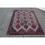 Eastern rug with repeat lozenge in multiple tones on cream ground with flower-head borders,