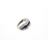 Sapphire and diamond ring with a central band of step cut blue sapphires flanked by a border of