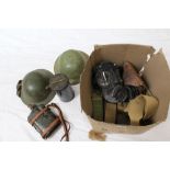 Two Second World War British Military tin helmets, together with canvas webbing,