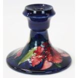 Moorcroft pottery candlestick decorated in the Orchid pattern on blue ground,
