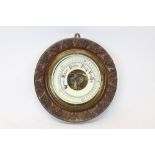 Early 20th century aneroid barometer with enabled dial in a circular carved oak case,
