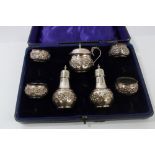 Late Edwardian / early George V silver six piece condiment set with raised floral decoration -