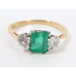 Emerald and diamond three-stone ring with a step cut emerald estimated to weigh approximately 1.