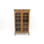 1920s walnut floor-standing bookcase enclosed by pair of shaped astragal glazed doors,