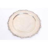 Peruvian white metal dining plate of circular form, with scroll and shell border and dished centre,