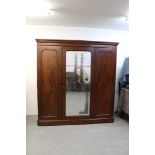 Victorian mahogany triple wardrobe with moulded cornice and centred by mirrored panelled door