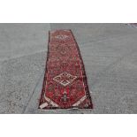 Hamadan runner with three medallions and geometric ornament on brick-red ground,