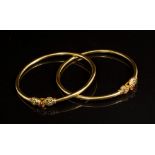 Two Indian yellow metal bangles, each set with rubies,
