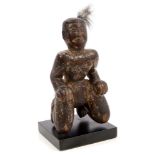 Antique tribal carved and painted wooden kneeling figure, on display stand,