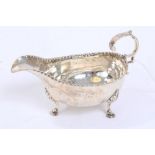 George IV silver sauce boat of small proportions, with punched rim and open scroll handle,