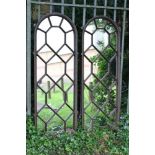 Pair of cast iron mirrored panels of arched form, with repeat lozenge pattern,
