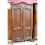 19th century French carved chestnut armoire enclosed by a shaped pair of floral carved panelled