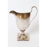 George III silver helmet-shaped cream jug with spot-punched rim, engraved monogram and loop handle,