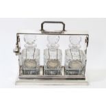 Stylish early 20th century silver plated tantalus, the locking bar with surmounting carrying handle,