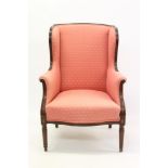 Edwardian mahogany wing armchair upholstered in salmon-pink fabric,