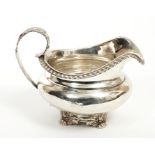 George IV silver cream jug of compressed baluster form, with gadrooned border, engraved armorial,