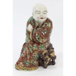 Late 19th century Japanese porcelain figure of a scholar wearing a floral robe, seated on a rock,