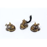 Interesting group of three miniature military helmets - possibly charms - comprising one French and