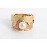 Two-colour yellow metal wide band ring set with a single cultured pearl.
