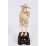 Late 19th century Japanese carved ivory figure of a fisherman, on hardwood stand,