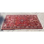 Eastern rug, brick-red ground with scattered foliate branch-work in flower-head borders,