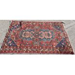 Antique Heriz rug, brick-red field centred by concentric floral medallions and angular foliage,