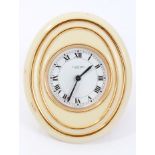 1980s Cartier alarm clock with circular white enamel dial and cream and gilt oval case with easel