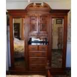 Edwardian mahogany compactum wardrobe with central carved cupboards and two short drawers over open
