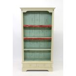Cream painted open bookcase with two drawers below on bracket feet,