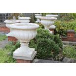 Set of six classical-style concrete garden urns of squat campagna form on integral square base,