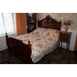 Late nineteenth century French walnut double bed with pierced and carved arched headboard and