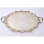 George V silver twin handled tray of shaped oval form with shell and scroll borders,