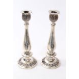 Pair of Thai silver candlesticks with baluster columns decorated with Thai deities and leaf