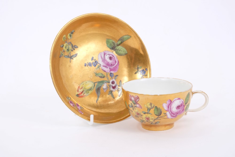 Mid-18th century Meissen gold ground tea cup and saucer with polychrome painted floral sprays -